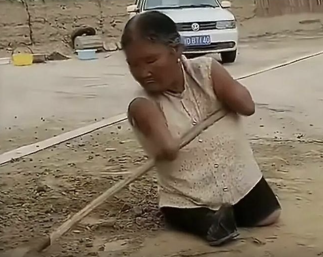 팔뚝에 빗자루를 끼워 비질을 하고 있는 왕위시씨. 바이두 캡처