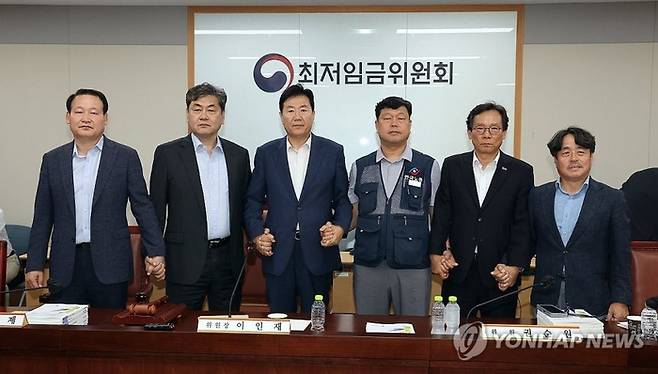 이인재 최저임금위원장(왼쪽 두 번째)이 지난해 7월 10일 정부세종청사에서 열린 제12차 전원회의에서 내년 최저임금을 시간당 1만320원으로 17년만에 합의로 결정한 뒤 공익위원-사용자위원-근로자위원과 손을 잡고 있다. [연합뉴스]