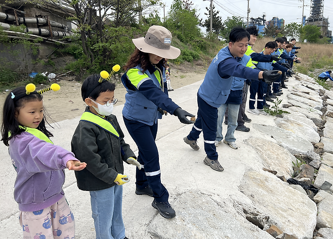 22일 ‘퓨처엠 Nature Guard Day’ 봉사활동에 참여한 포스코퓨처엠 직원과 가족들이 씨드볼을 만들어 포항시 남구 냉천에 던지고 있다. /포스코퓨처엠 제공