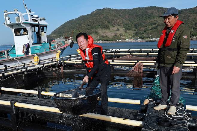 정청래 더불어민주당 대표가 지난 21일 경남 통영시의 한 욕지도 양식장을 방문해 뜰채로 우럭을 잡아보고 있다. 연합뉴스