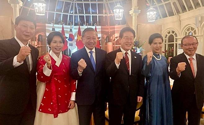 이재명 대통령(왼쪽 4번째)과 김혜경 여사(왼쪽 2번째), 또 럼 베트남 공산당 당서기(왼쪽 3번째)와 부인인 응오 푸엉 리 여사(오른쪽 2번째), 박항서 전 감독(맨 오른쪽)과 김상식 감독(맨 왼쪽)이 함께 주먹을 쥐고 촬영한 기념사진. (사진, 이재명 대통령 SNS)