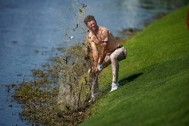 24일 미국 루이지애나주 애번데일의 TPC루이지애나에서 열린 PGA 투어 취리히 클래식 1라운드 18번홀에서 마이클 브레넌이 윗옷을 벗고 샷 했다. 진흙, 물풀 등과 함께 튄 공은 다시 물속으로 떨어지고 있다. /AP 연합뉴스