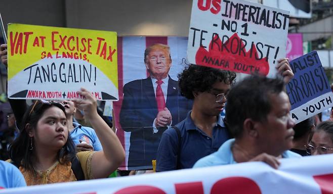 15일 필리핀 수도 마닐라에서 미국·이스라엘과 이란 전쟁 발발 뒤 심해지고 있는 에너지 부족과 고유가에 항의하는 시위가 열렸다. 시위대가 도널드 트럼프 미국 대통령의 사진과 미국을 비판하는 내용이 적힌 팻말을 들고 있다. 원유의 90% 이상을 중동에서 수입하는 필리핀은 지난달 휘발유 가격 폭등에 직면해 국가비상사태를 선포했다. 마닐라=AP 뉴시스