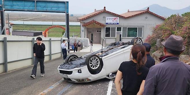 전남 화순소방서 동복119안전센터 강성중 소방교(차량 왼쪽)가 11일 오후 6시 반경 전남 순천시 순천만길 경사진 도로에서 전복된 승용차에서 할머니를 구조한 후 상황을 알리고 있다. 전남소방본부 제공