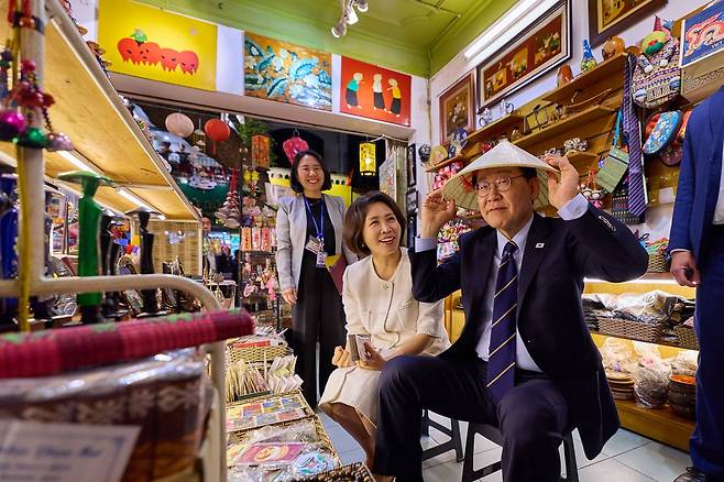 베트남을 국빈 방문중인 이재명 대통령과 김혜경 여사가 23일(현지시간) 저녁 베트남 하노이 도심 거리 산책도중 상점에 들어가 베트남 전통 모자인 '논라'를 착용해보고 있다. 청와대사진기자단