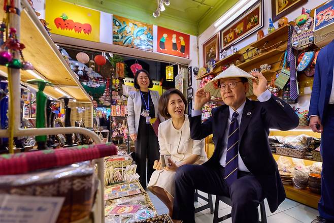 ▲ 청와대는 베트남을 국빈 방문 중인 이재명 대통령과 김혜경 여사가 23일(현지시간) 하노이 호안끼엠 호수 인근 한 상점을 방문해 베트남 전통 모자인 논라를 써보는 모습을 24일 SNS에 공개했다. 2026.4.24 [이재명 대통령 SNS]