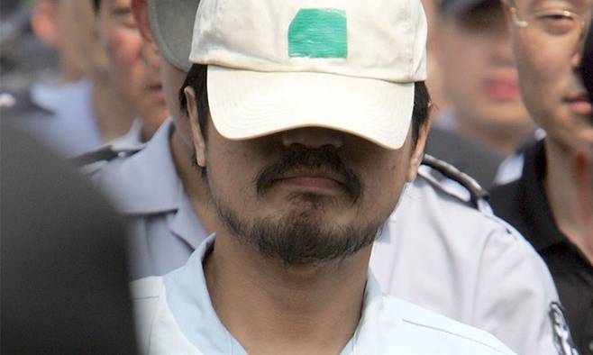 지난 2004년 8월 서울 서대문구 봉원사 뒤편 야산에서 연쇄살인범 유영철이 경찰·검찰 관계자들과 함께 현장 진술을 하고 있다. 연합뉴스