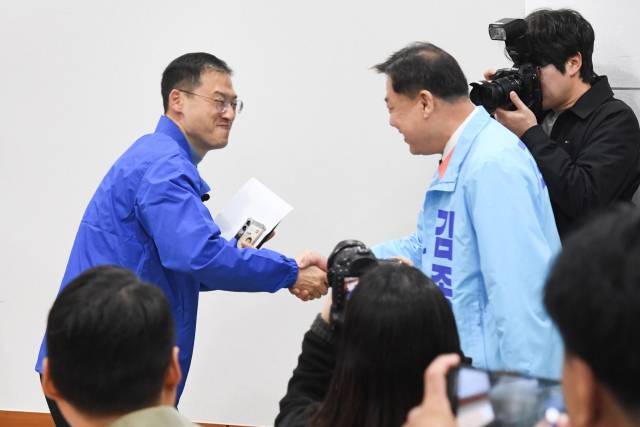 지난달 25일 울산시의회 프레스센터에서 더불어민주당 김상욱(왼쪽) 의원과 진보당 김종훈 전 동구청장이 우연히 만나 악수하는 모습. 연합뉴스