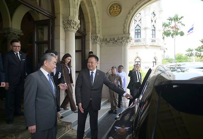 24일 방콕 정부 청사에서 아누틴 찬위라꾼(오른쪽) 태국 총리가 왕이(왼쪽) 중국 외교부장과 회담 후 중국산 전기자동차 BYD 차량 문을 열어주고 있다. 이날 아누틴 총리는 직접 BYD를 운전해 오찬장소로 이동했다. EPA=연합뉴스