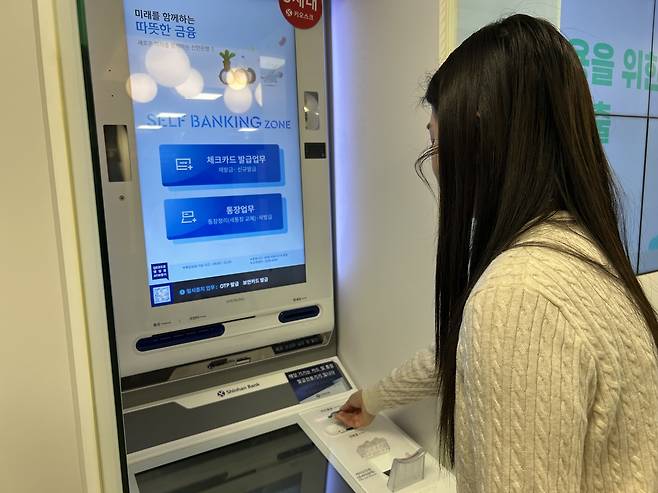 베트남인 부튀링 씨가 지난 23일 서울 중구 서소문에 있는 신한은행 인공지능(AI) 브랜치에서 디지털 데스크를 통해 실시간 AI 통번역 서비스를 바탕으로 체크카드를 발급받은 뒤 무인 카드발급기를 통해 실물 카드를 받고 있다. [김은희 기자]