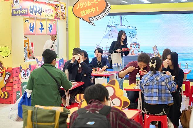 지난 16일 일본 도쿄 이케부쿠로에서 열린 '코리아엑스포' 너구리 부스에서 일본인들이 너구리를 맛보고 있다. 농심 제공