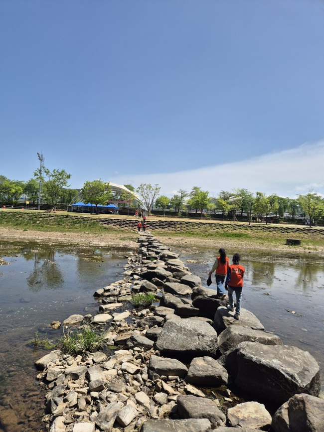 ▲ 26일 경북 의성군 구봉공원 일대에서 열린 의성군 의성읍 상인회 산행·야유회에서 회원들이 하천 돌다리를 건너고 있다. 이날 참가자들은 구봉산 산행과 함께 주변 환경정비 활동을 진행하며 출범 이후 첫 단합행사의 의미를 더했다. 의성삼거리기름방 제공.