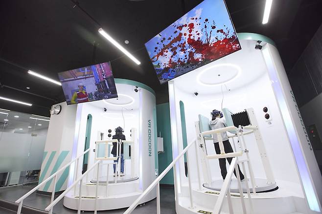 취재진이 'VR 코쿤'을 통해 통신 공사 현장의 안전 사고 체험을 하고 있다.
