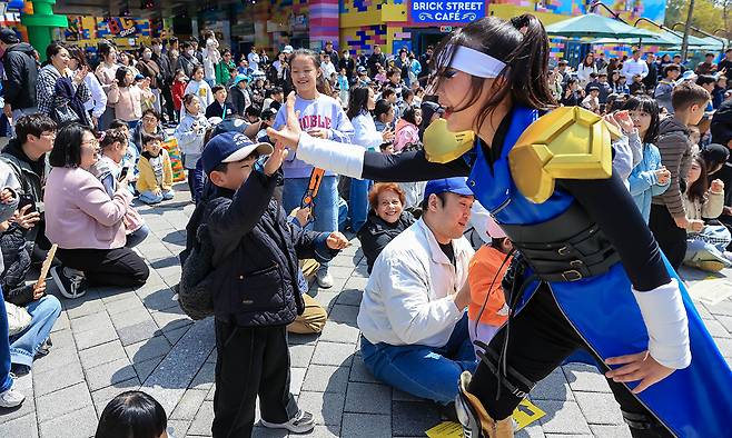 “여기여기 붙어라” 24일 강원 춘천 레고랜드를 찾은 가족 단위 관광객들이 브릭스트리트 원형 광장에서 열린 ‘세리머니 닌자’ 공연을 관람하며 즐거운 시간을 보내고 있다. 레고랜드 제공