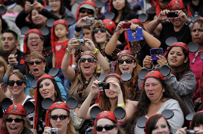 2011년 5월 7일, 캘리포니아주 애너하임 디즈니랜드에서 열린 영화 ‘캐리비안의 해적: 낯선 조류’ 월드 프리미어 현장에서 미키 마우스가 도착하자 팬들이 환호하며 사진을 찍고 있다. AP/뉴시스