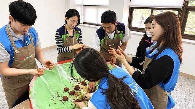 에어부산·진에어 객실승무원들이 지난 27일 지역 사회 환경 개선을 위한 'EM 흙공 만들기' 봉사를 하고 있다. 에어부산 제공