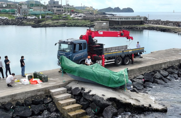 해경과 경찰 등이 제주시 한경면 용수리 해안가에서  발견된 미확인 보트를 조사해 인양하려 하고 있다. 연합뉴스