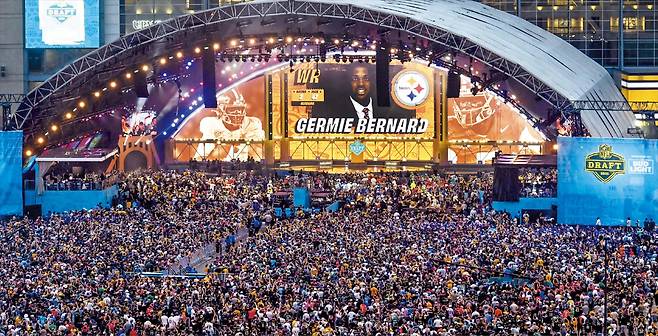 2026 NFL 드래프트 둘째 날인 25일(한국 시각) 미국 피츠버그 애크리슈어 스타디움에 수만 명의 풋볼 팬이 몰렸다. 피츠버그가 연고지인 스틸러스가 2라운드 전체 47번째로 와이드 리시버 저미 버나드를 지명하는 모습. 사흘간 진행된 드래프트 행사에 역대 최다인 80만5000명이 피츠버그를 방문해 지역 경제에 활기를 불어넣었다. /UPI 연합뉴스