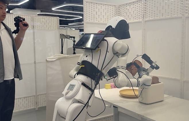 28일 베이징 스징산구 베이징인간형로봇데이터훈련센터에서 로봇이 식빵을 토스터에 넣는 동작을 수행하고 있다. 베이징/이정연 특파원