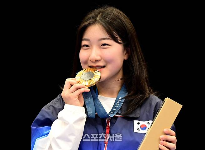 사격 국가대표 반효진이 29일(한국시간) 프랑스 샤토루 슈팅센터에서 열린 2024 파리올림픽 공기소총 10ｍ 여자 개인전에서 황위팅(중국)과 접전을 벌이며 올림픽 신기록으로 1위를 차지한 뒤 시상대 위에서 금메달을 물어보이며 기념촬영을 하고 있다. 샤토루 | 박진업 기자 upandup@sportsseoul.com