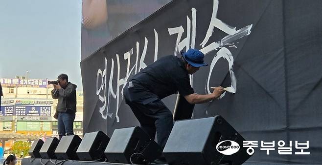 1일 오후 노동절을 맞아 민주노총 경기도본부가 수원역 앞에서 주최한 '2026 세계노동절 경기대회' 참여자가 본무대에 "열사정신 계승" 표어를 작성하고 있다. 최진규 기자