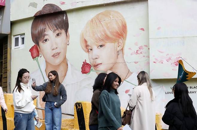 지난 3월 부산 서구 감천문화마을을 찾은 외국인 관광객들이 부산이 고향인 BTS 멤버 정국·지민이 그려진 대형 벽화를 배경으로 기념촬영하고 있다. 뉴스1 제공