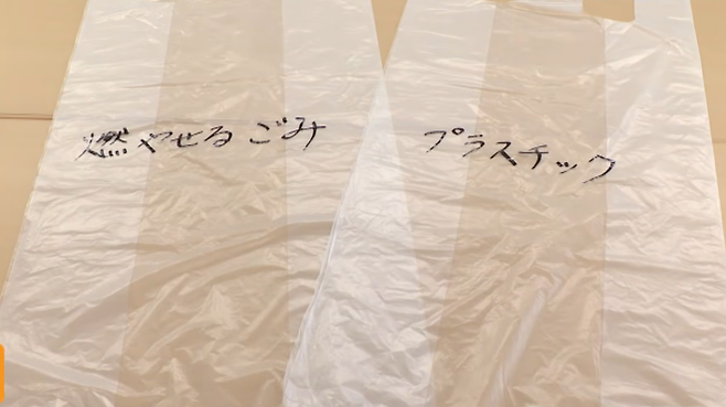오사키지역광역행정사무조합은 오사키시 등 5개 시·정(市·町)에 지난달 20일부터 한 달간 지정 쓰레기 봉투가 아니더라도 시중에 파는 30~45ℓ 크기의 투명 또는 반투명 봉투에 쓰레기 종류를 기재하면 배출할 수 있도록 했다. 사진은 그 예시. ‘타는 쓰레기’, ‘플라스틱’이라고 적혀 있다. FNN 보도화면 캡처