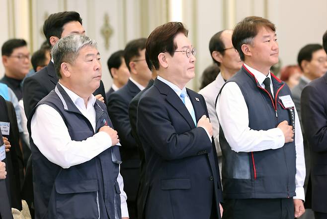 이재명 대통령이 1일 청와대 영빈관에서 열린 노동절 기념식에서 양대 노총 위원장을 비롯한 참석자들과 국민의례를 하고 있다. 왼쪽부터 김동명 한국노총 위원장, 이 대통령, 양경수 민주노총 위원장. 연합뉴스