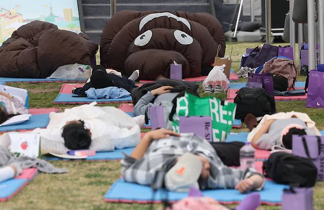 지난 2일 서울 영등포구 여의도한강공원 멀티플라자에서 열린 ‘2026 한강 잠퍼자기 대회’에서 참가자들이 똥 모양 옷을 입고 잠을 자고 있다. [연합뉴스]