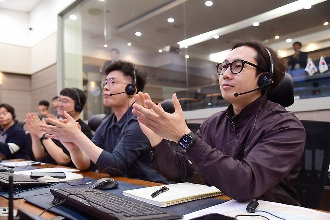 차세대중형위성 2호(위쪽)와 대전 한국항공우주연구원 지상국 연구진이 교신 성공후 박수를 치고 있는 모습. [한국항공주우주산업·우주항공청 제공]