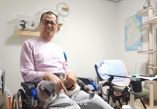뇌병변 장애인 김현수씨가 4월 28일 서울 동대문구 장안동 자신의 집 거실에서 반려묘 메주와 포즈를 취하고 있다. 이재덕 기자