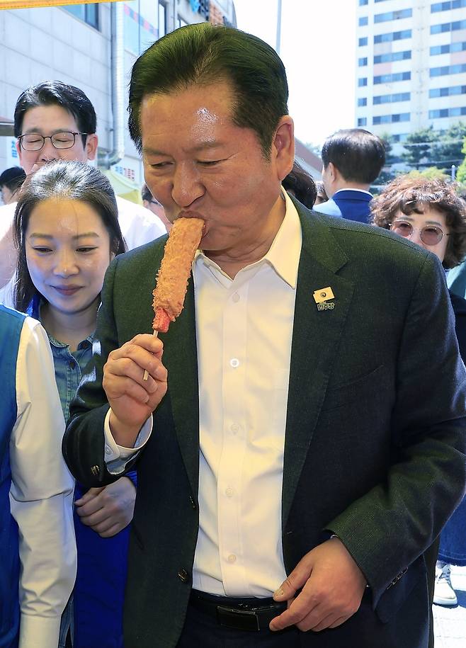 정청래 더불어민주당 대표가 5일 경기도 동두천시 중앙로 동두천큰시장에 이인규 동두천시장 후보 등과 함께 방문해 중간에 들린 어묵가게에서 어묵핫바을 사먹고 있다.  2026.5.5.뉴스1