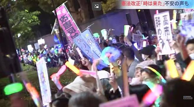 일본 시위대가 지난달 24일 도쿄 집권 자민당 당사 앞에서 응원봉과 깃발을 들고 다카이치 사나에 정부를 규탄하고 있다. TBS방송 유튜브 캡처