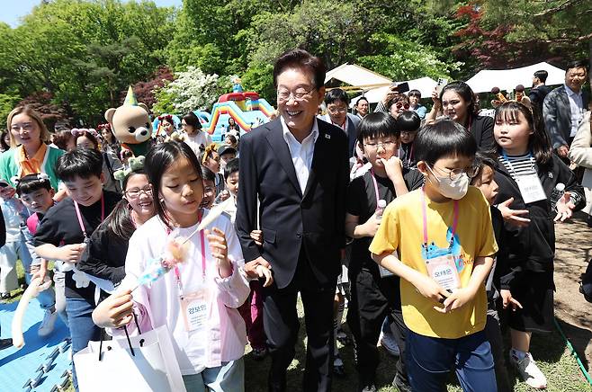 이재명 대통령과 김혜경 여사가 어린이들과 체험 활동을 위해 녹지원으로 이동하고 있다.