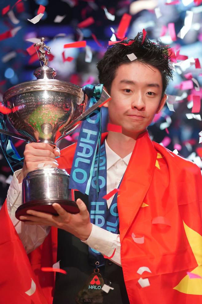 중국의 우이저가 4일 영국 셰필드 크루서블 시어터에서 열린 월드 스누커 챔피언십 결승에서 영국의 숀 머피를 꺾고 우승한 뒤 중국 국기를 두른 채 트로피를 들고 포즈를 취하고 있다. AP