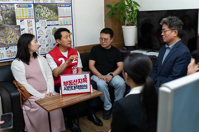 ▲오세훈 서울시장 후보가 6일 서울 성동구 행당동 부동산 정책 간담회에서 시민들과 대화를 나누고 있다. 테이블에는 '부동산지옥 시민대책회의' 문구가 놓여 있다. 사진=오세훈캠프 제공