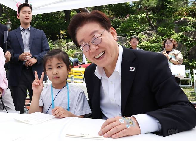 이재명 대통령이 지난 5일 청와대 녹지원에서 열린 어린이날 초청행사에서 참석 어린이에게 사인 후 기념촬영을 하고 있다. 연합뉴스