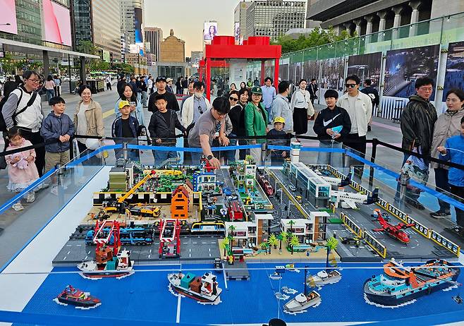 지난 5일 오후 서울 광화문광장에서 열리고 있는 '2026 광화문 가족동행축제-렛츠플레이 광화문광장'에서 작가가 전시된 작품을 해체하기 전 한 어린이에게 줄 작품을 고르고 있다. /남강호 기자