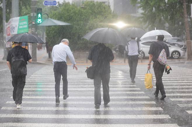 서울 영등포구 여의도 국회 인근에서 시민들이 우산을 쓰고 이동하고 있다.[연합]