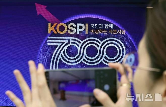 [부산=뉴시스] 하경민 기자 = 사상 처음으로 코스피 7000p를 돌파한 6일 부산 남구 부산국제금융센터 내 한국거래소 홍보관에서 열린 축하행사에 참석한 한 관계자가 휴대전화로 촬영하고 있다. 2026.05.06. yulnetphoto@newsis.com
