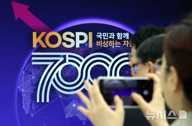 [부산=뉴시스] 하경민 기자 = 사상 처음으로 코스피 7000p를 돌파한 6일 부산 남구 부산국제금융센터 내 한국거래소 홍보관에서 열린 축하행사에 참석한 한 관계자가 휴대전화로 촬영하고 있다. 2026.05.06. yulnetphoto@newsis.com