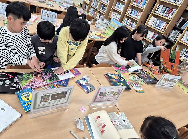▲&nbsp;수원동신초등학교 학생들이 별별 책 전시회에 전시된 책들을 체험하고 있다. /사진제공=수원동신초등학교