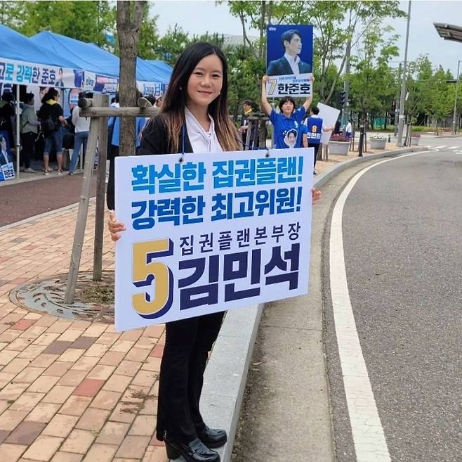 2024년 7월20일 인천시당 당원대회가 열린 인천 남동체육관 앞에서 이본아 선대위원장이 김민석 당시 수석최고위원 후보의 선거 유세를 위한 팻말을 들고 있다. 사진 이본아