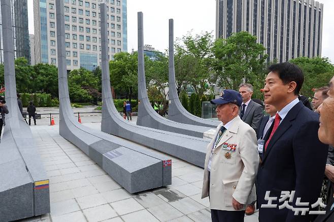 국민의힘 오세훈 서울시장 후보가 12일 서울 광화문광장에서 열린 '감사의 정원 준공식'에 참석해 6.25 참전유공자와 석재 조형물을 보고 있다. 황진환 기자