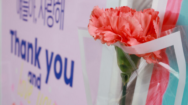 지난 2025년 5월 15일 서울 성동구 서울방송고등학교에서 등교하는 학생들을 맞이하는 교사가&nbsp;카네이션과 손팻말을 들고 있다. 연합뉴스