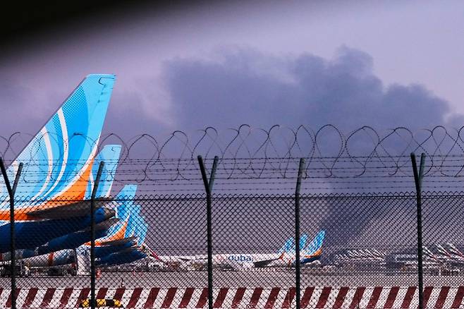 3월 16일 아랍에미리트(UAE) 두바이 국제공항 인근에서 드론이 연료 탱크를 타격해 연기가 치솟는 가운데 공항에 플라이 두바이 소속 항공기들이 계류하고 있다. 이란은 전쟁기간 걸프 연안국들에 대한 공습을 계속했다. 2026.05.13 [두바이=AP/뉴시스]