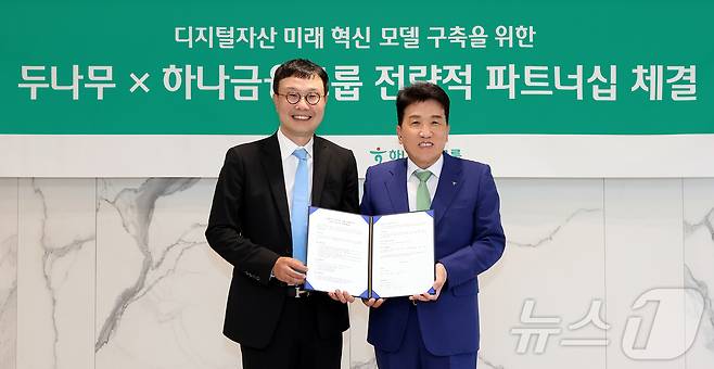 하나금융그룹이 주요 관계사인 하나은행을 통해 국내 최대 가상자산 인프라를 보유한 두나무에 대한 1조원 규모 지분을 취득하고, 금융과 디지털자산을 연계한 미래혁신모델 구축을 위한 전략적 업무협약을 체결했다고 15일 밝혔다. 이날 협약식에 참석한 함영주 하나금융그룹 회장(오른쪽)이 김형년 두나무 부회장과 함께 협약서를 들고 기념촬영을 하고 있다. (하나은행 제공. 재판매 및 DB금지) 2026.5.15 ⓒ 뉴스1