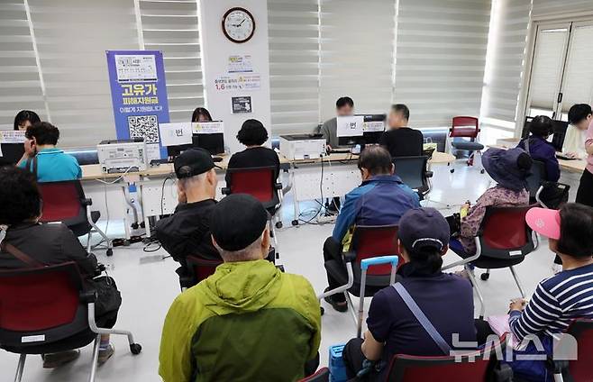[부산=뉴시스] 하경민 기자 = 정부 고유가 피해지원금 2차 신청·지급 첫날인 18일 부산 부산진구 개금3동행정복지센터에서 주민들이 선불카드형 지원금을 받고 있다. 2026.05.18. yulnetphoto@newsis.com