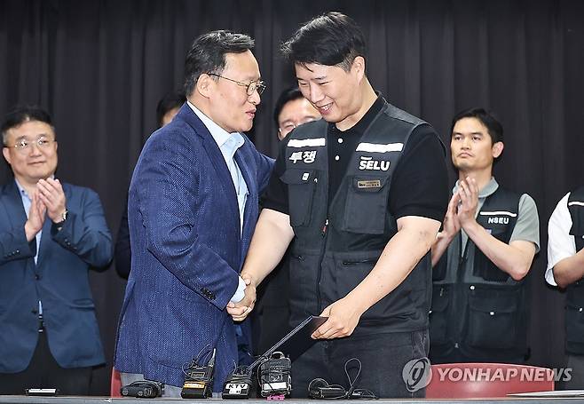 삼성전자 파업 유보 (수원=연합뉴스) 홍기원 기자 = 20일 경기도 수원시 장안구 경기고용노동청에서 열린 삼성전자 임금협상을 마친 후 여명구 삼성전자 DS(디바이스솔루션·반도체 사업 담당) 피플팀장과 최승호 삼성그룹 초기업노동조합 삼성전자지부 위원장이 잠정 합의안에 서명한 후 손을 맞잡고 있다. 2026.5.20 [공동취재] xanadu@yna.co.kr