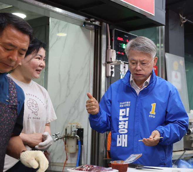 더불어민주당 민형배 전남광주통합특별시장 후보가 21일 오전 6시 광주 서구 양동시장을 방문해 상인들과 인사를 나눴다.사진은 구매한 생고기를 맛본 뒤 '엄지 척' 하고 있는 민 후보. /김성빈 기자 ksb@namdonews.com